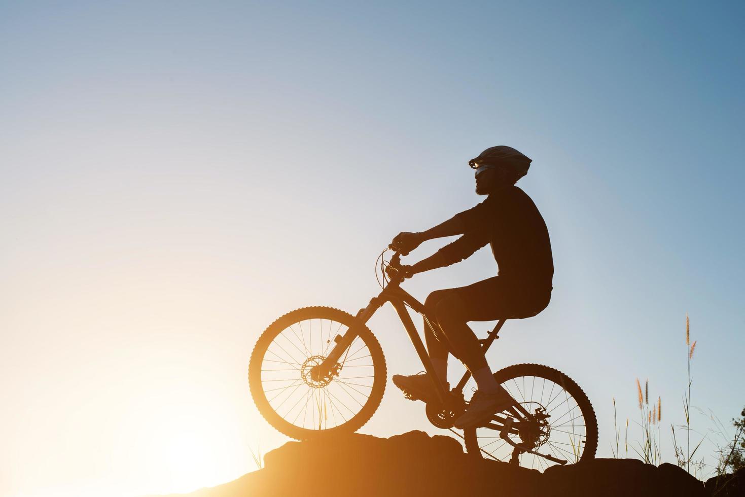 silhueta de um homem em mountain bike durante o pôr do sol. foto