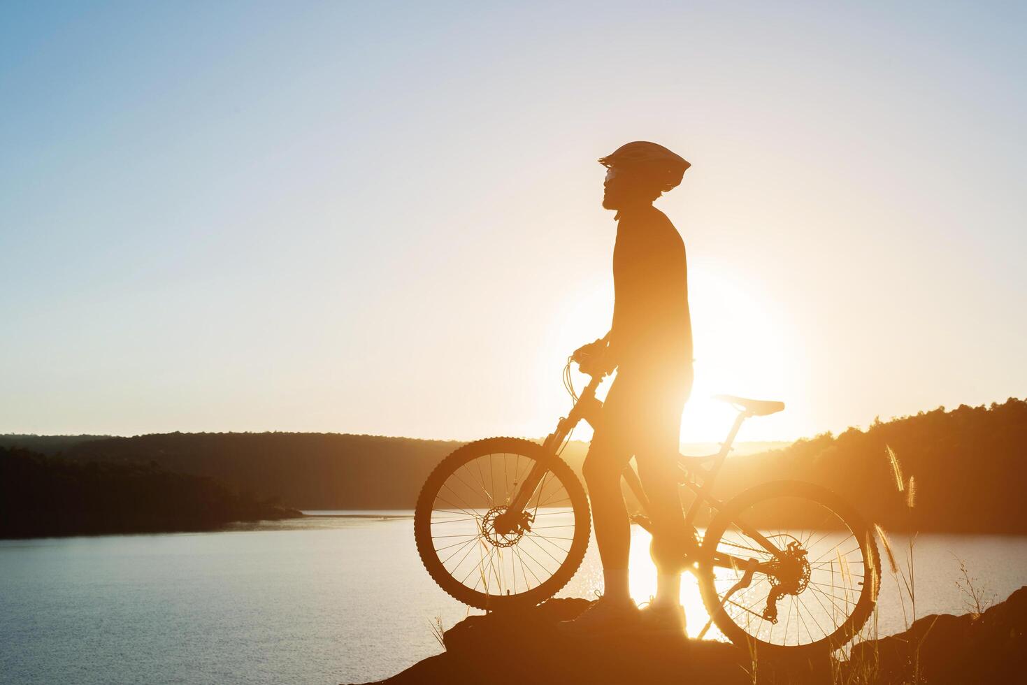 silhueta de um homem em mountain bike durante o pôr do sol. foto