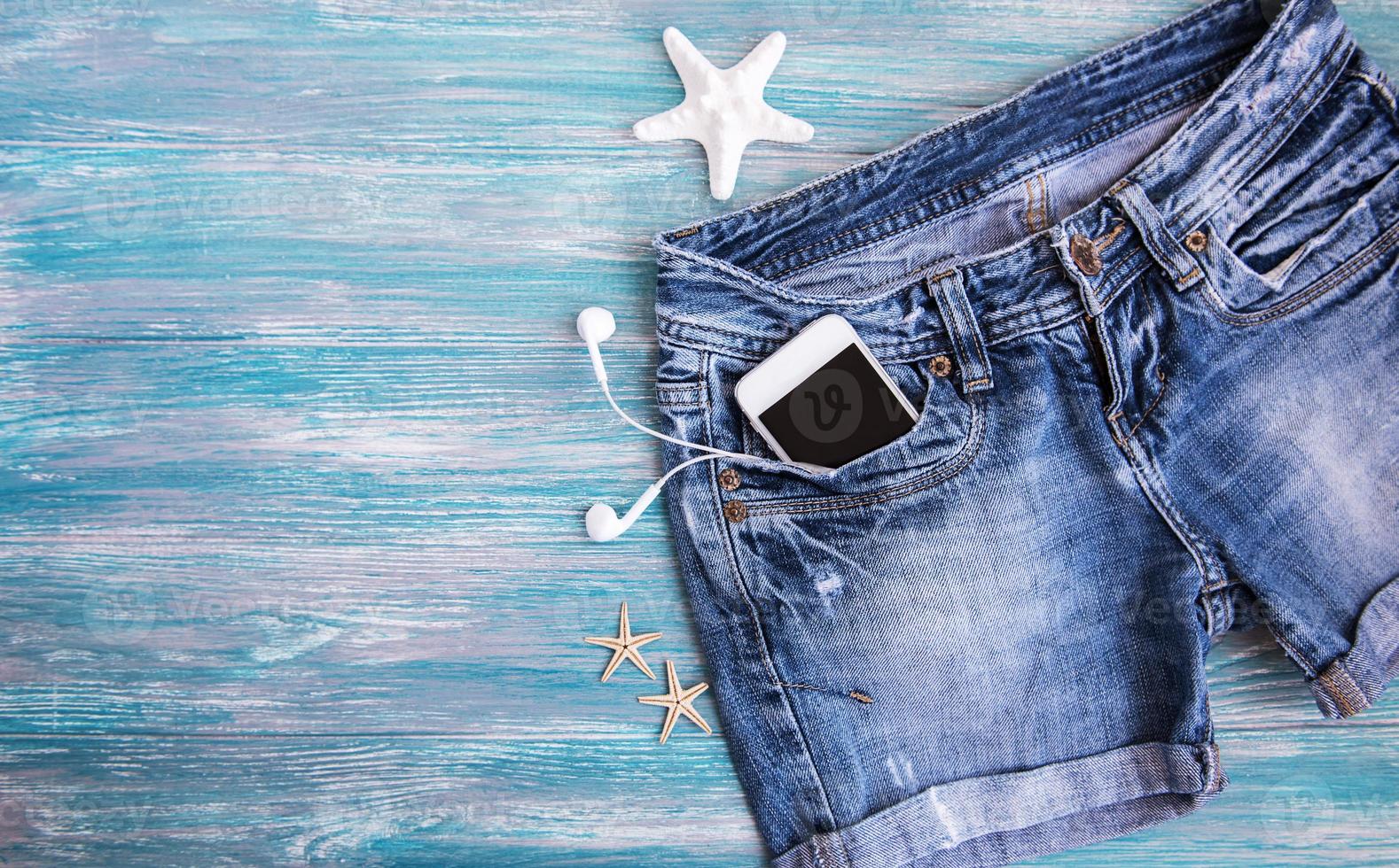 shorts jeans, telefone celular, fones de ouvido, conchas foto