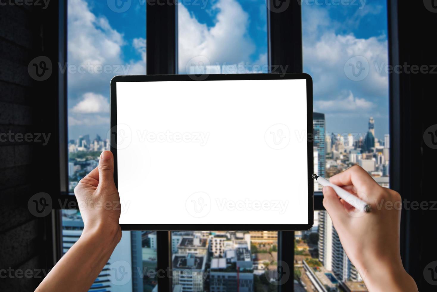 uma mulher usando tablet de tela em branco com caneta na mesa de escritório moderna escura com material de escritório foto