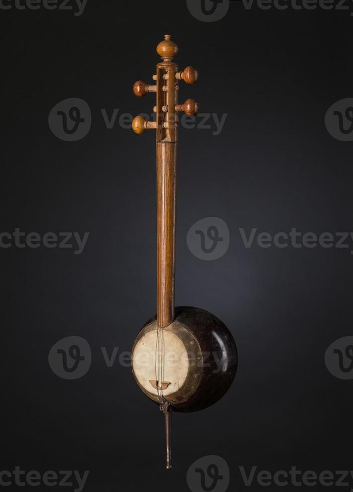 antigo instrumento musical de cordas asiático em fundo preto com luz de fundo foto