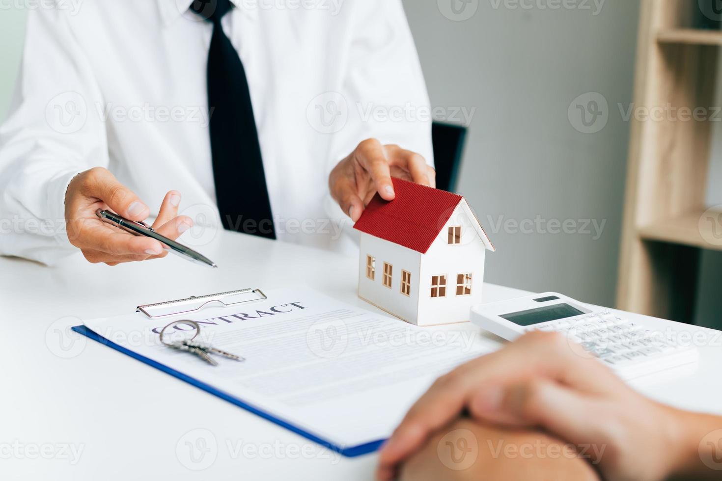 agentes residenciais estão enviando canetas para clientes assinando um contrato para comprar uma nova casa. foto