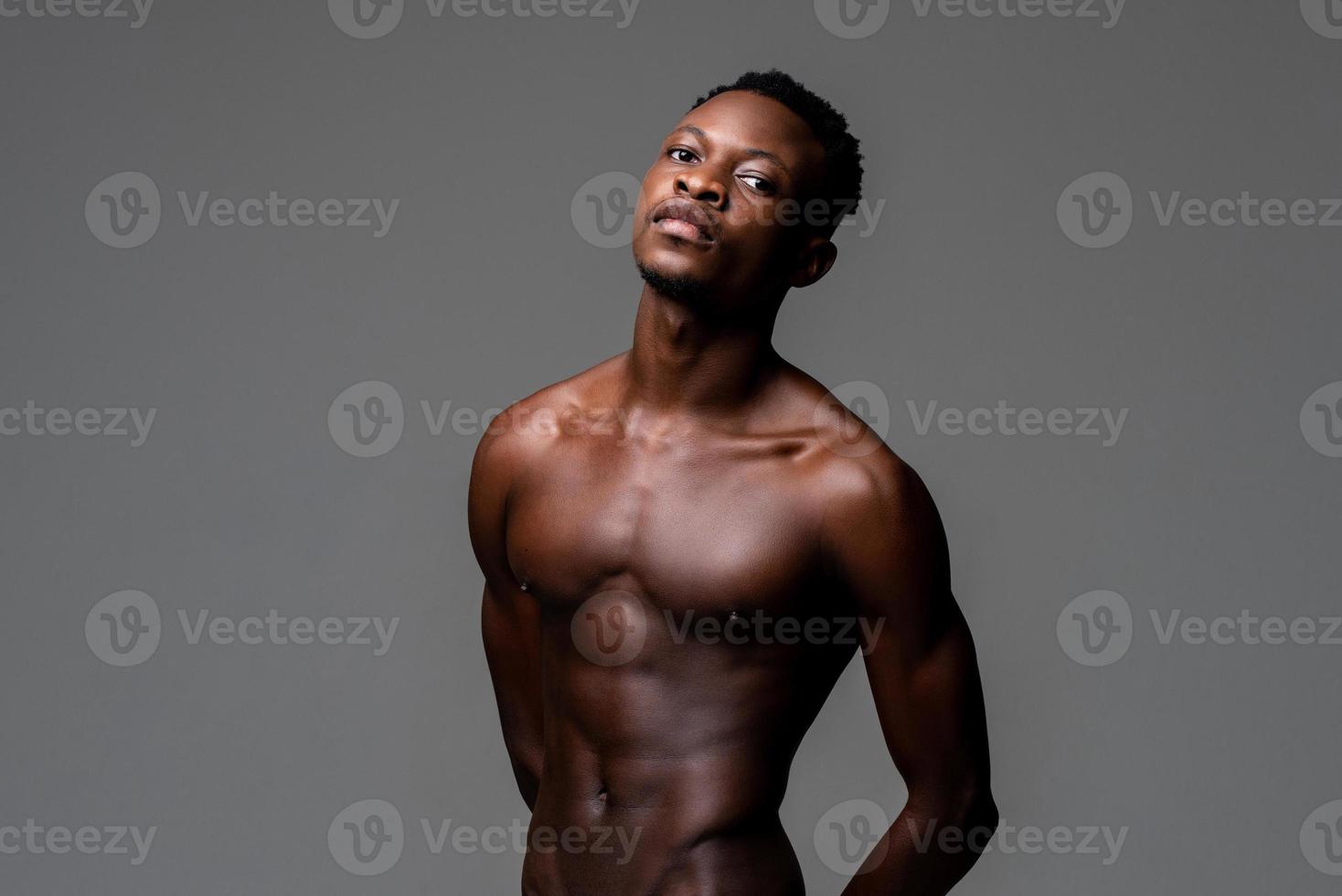 cintura para cima retrato de estúdio de um jovem africano magro sem camisa em fundo cinza claro isolado foto