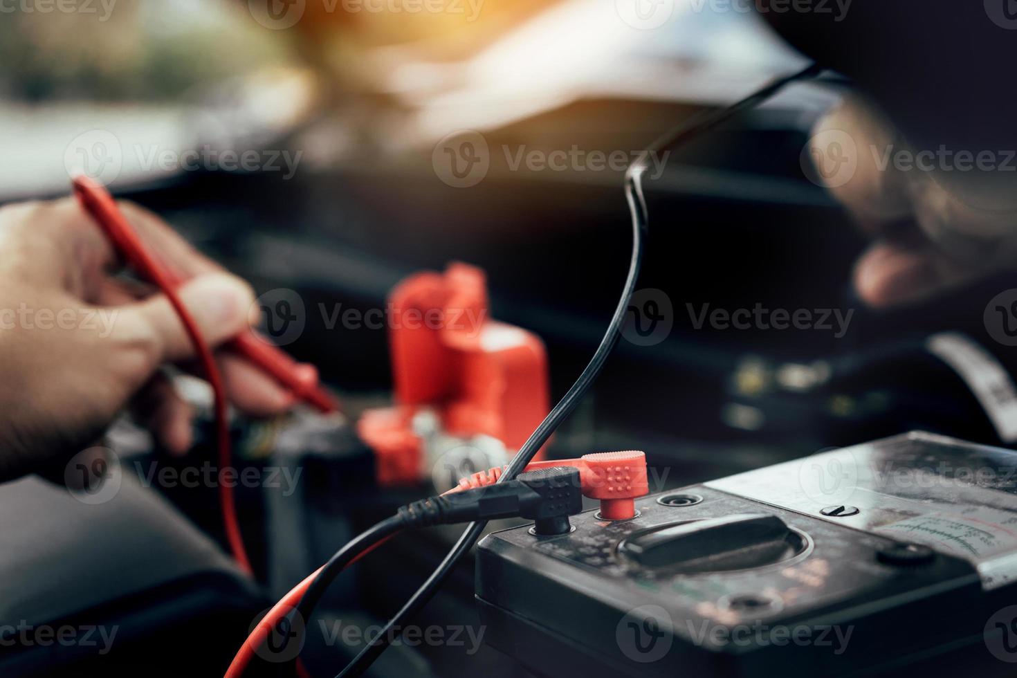 mecânico de automóveis está usando o medidor de bateria do carro para medir vários valores e analisá-lo. foto