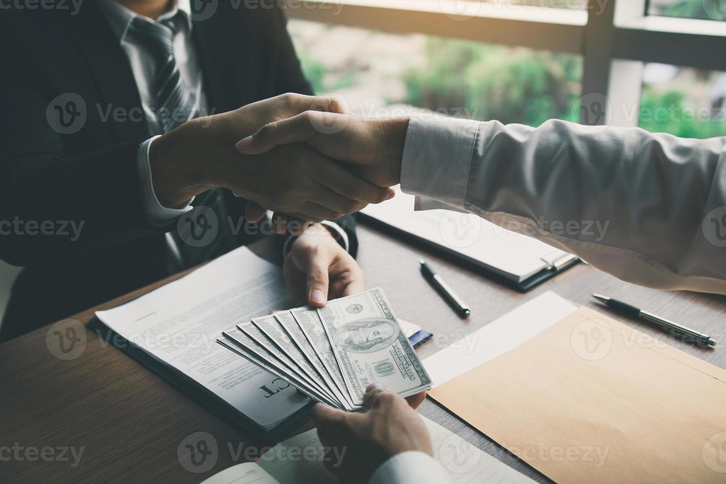 dois empresários corporativos apertando as mãos enquanto um homem dá dinheiro e recebe dinheiro sujo na sala de escritório com o conceito de corrupção. foto