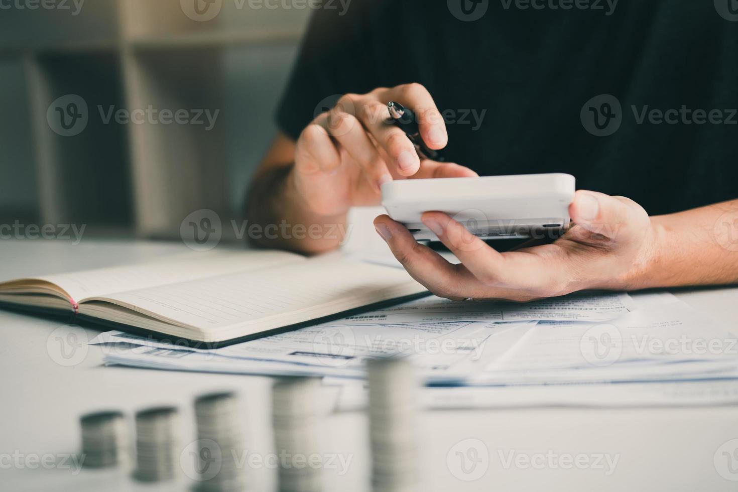 homem usa calculadoras e documentos que calculam despesas no escritório em casa. foto