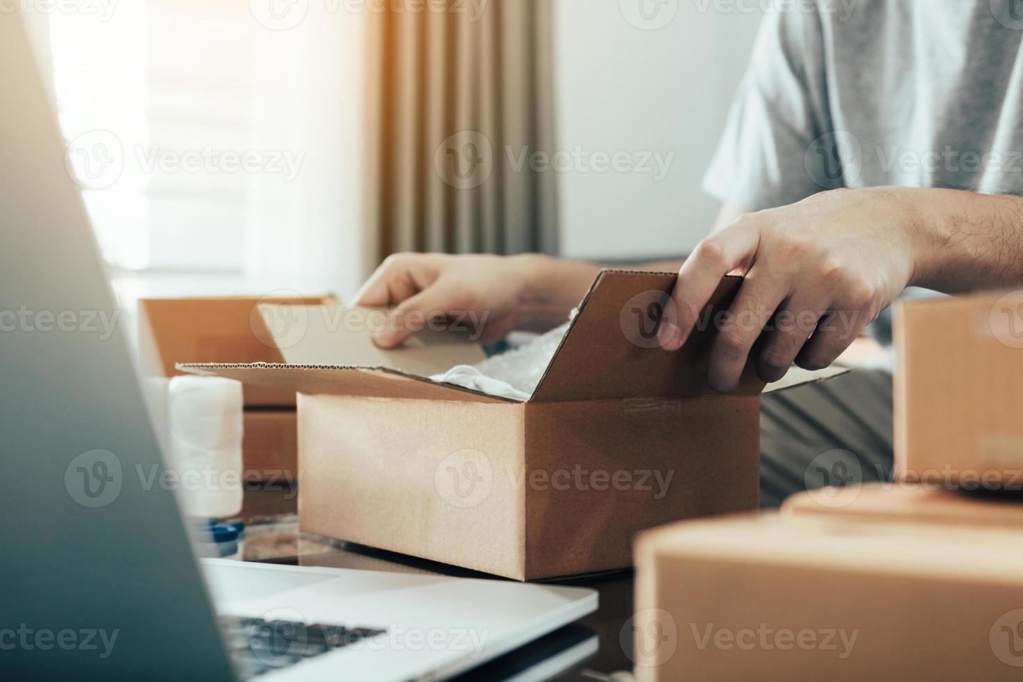 adolescente empresário asiático está abrindo uma caixa de papelão para colocar o produto que o cliente pediu na caixa para entregar o produto. foto