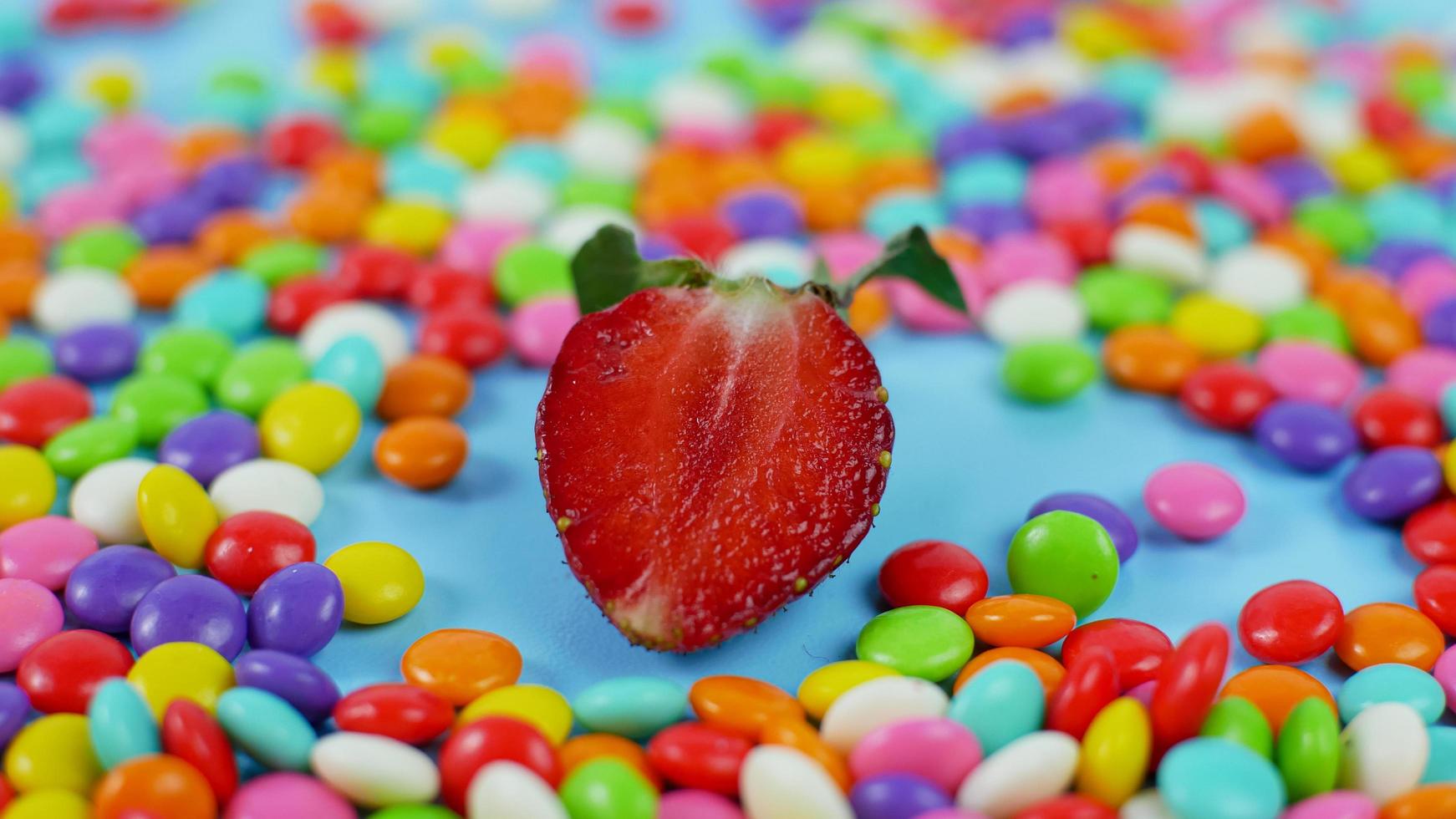 morango entre doces coloridos sobre fundo azul pastel foto