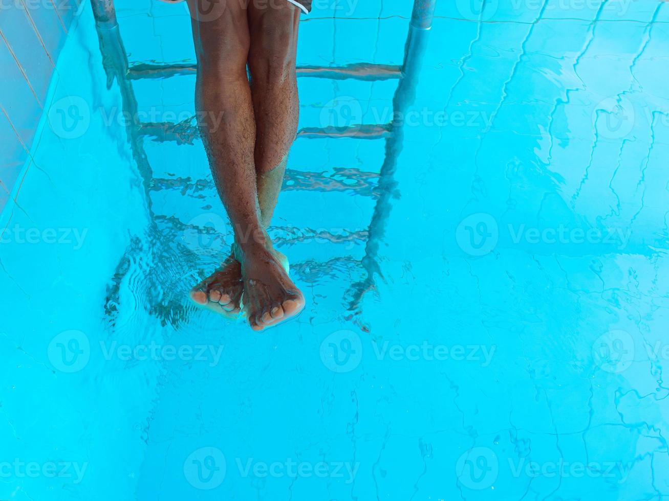 as pernas do homem afro-americano adulto debaixo d'água na piscina foto