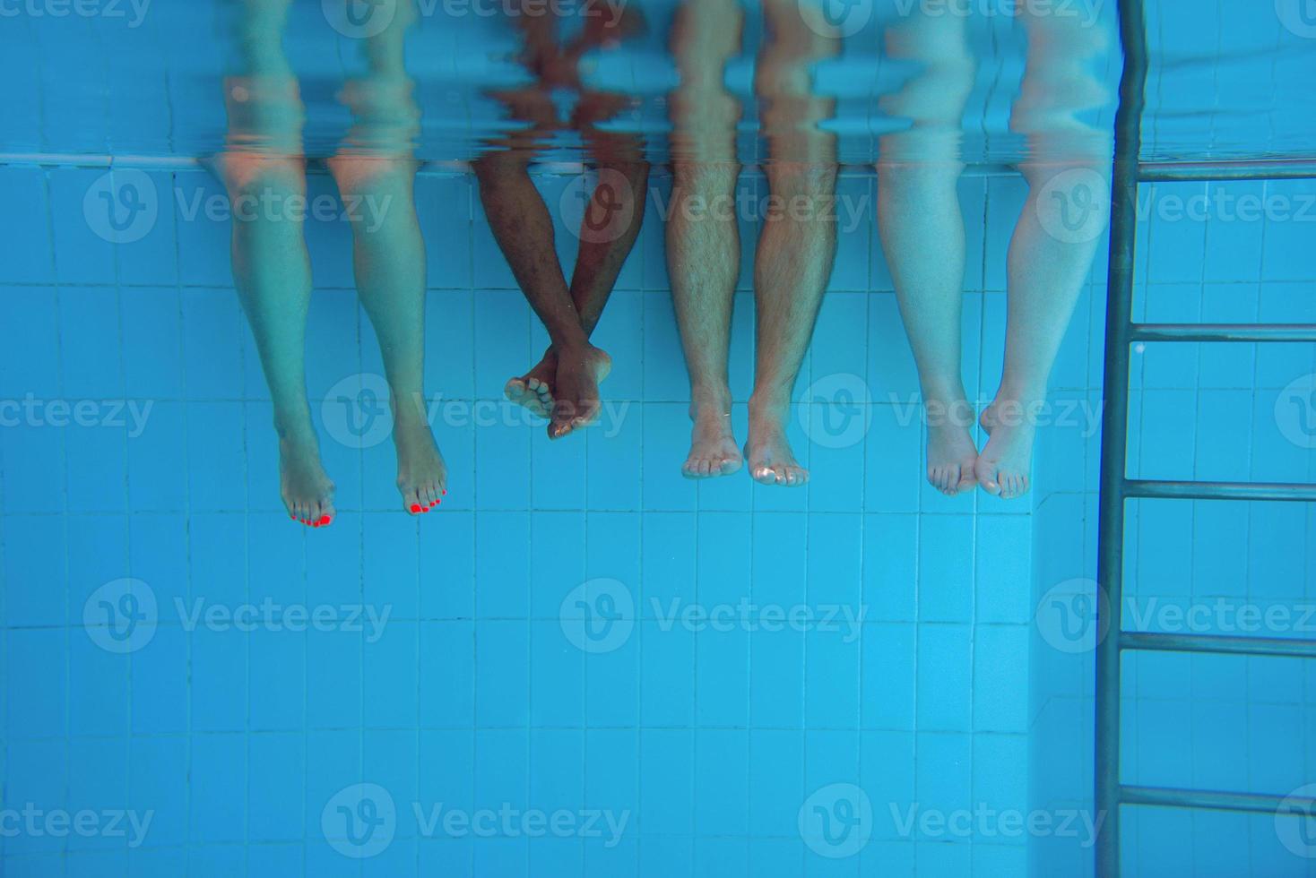 pernas de homem afro-americano com amigos caucasianos na piscina debaixo d'água. verão. conceito de férias, internacional e esporte. foto