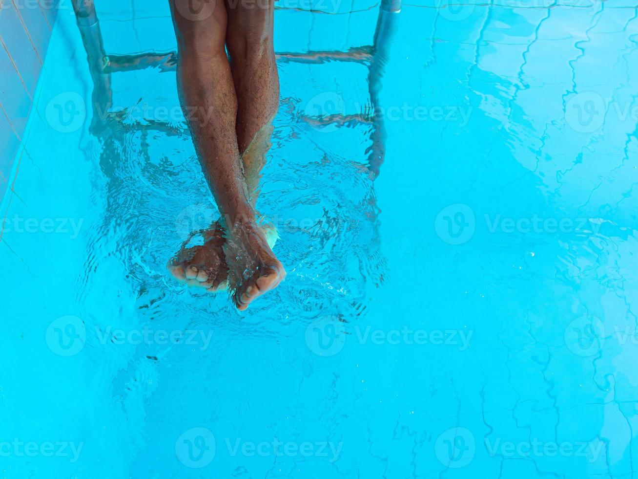 as pernas do homem afro-americano adulto debaixo d'água na piscina foto