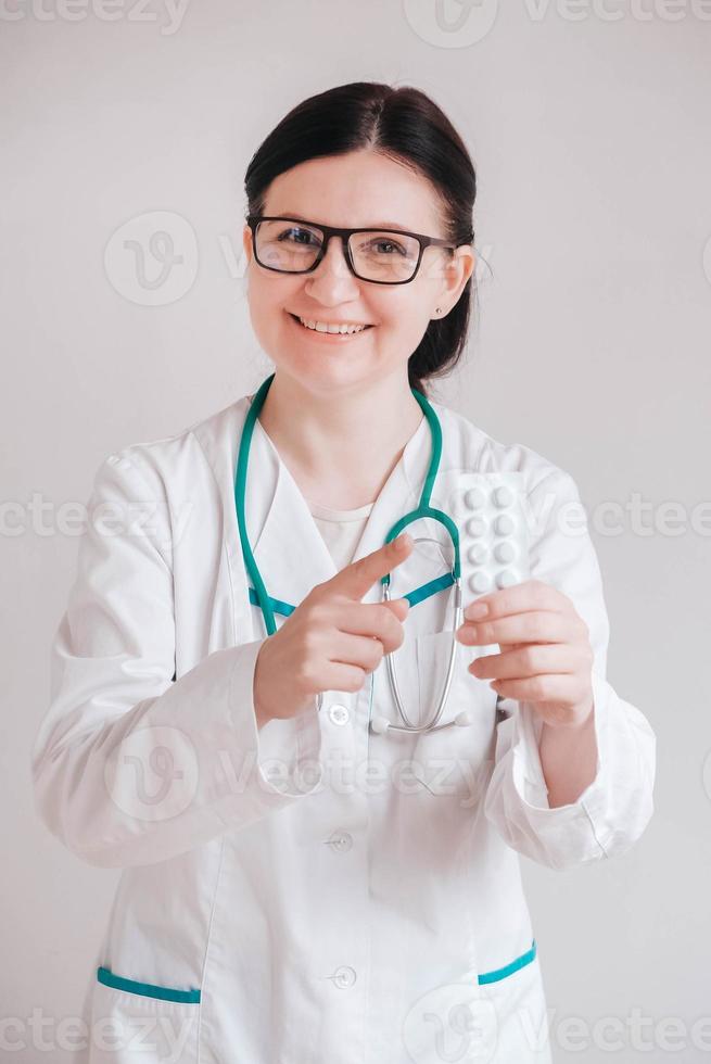 médica mulher com comprimidos nas mãos em um fundo branco. tomar vitaminas ou medicamentos. copiar, espaço vazio para texto foto