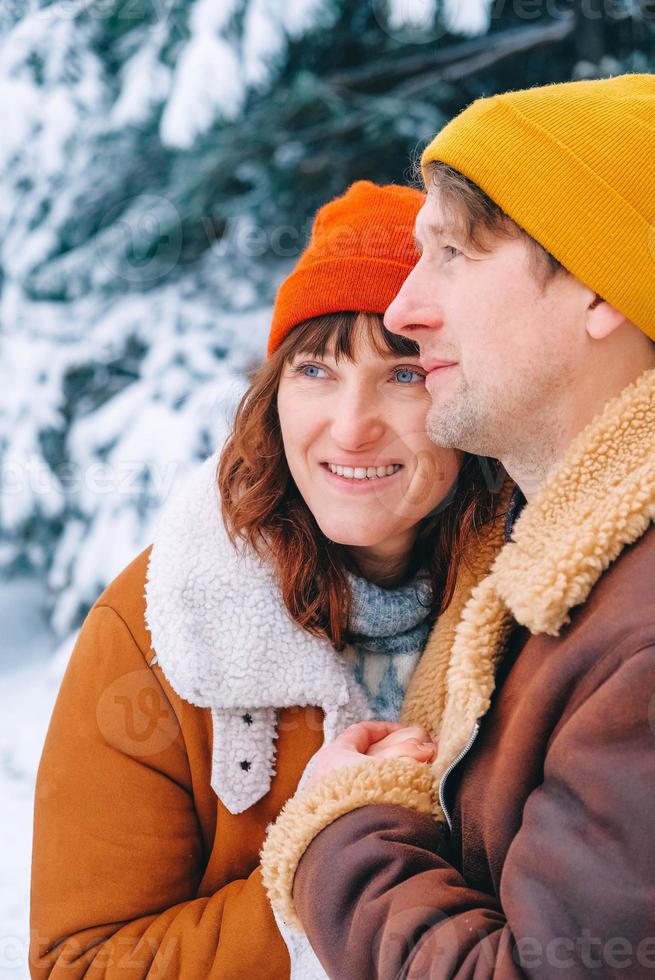 casal homem e mulher abraçando em um fundo de floresta nevada foto