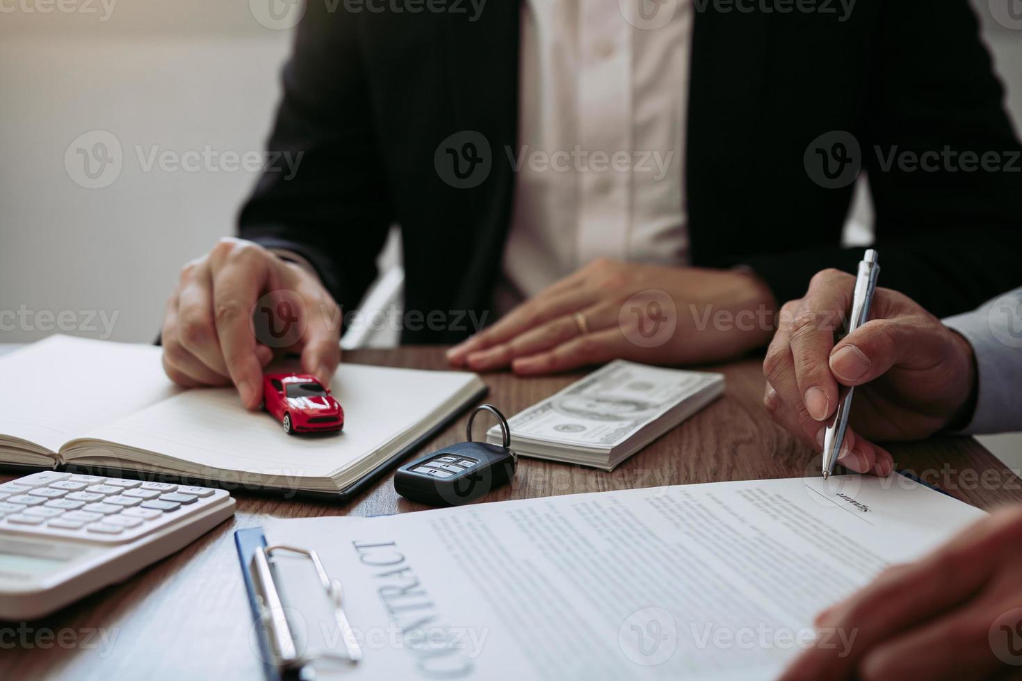 O vendedor de carros do agente entregou o carro modelo de brinquedo ao comprador do carro novo enquanto assinava o contrato. foto
