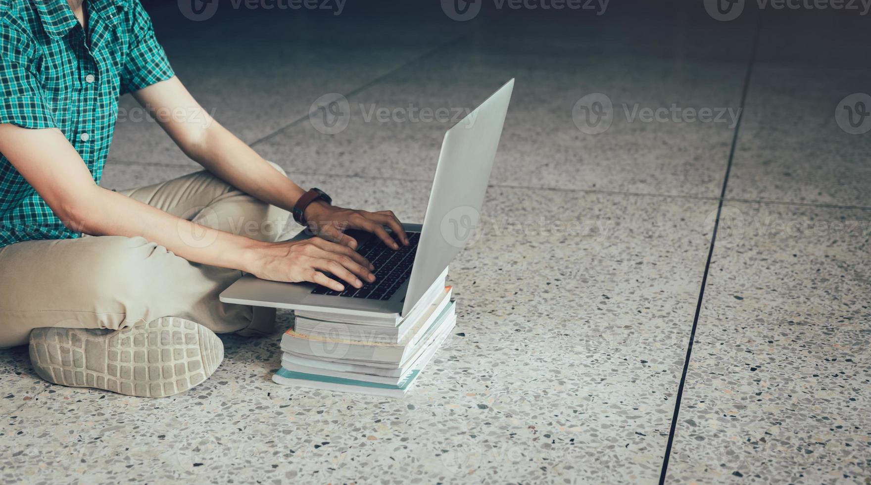 estudante adolescente sentado no chão usando o computador portátil na biblioteca. foto