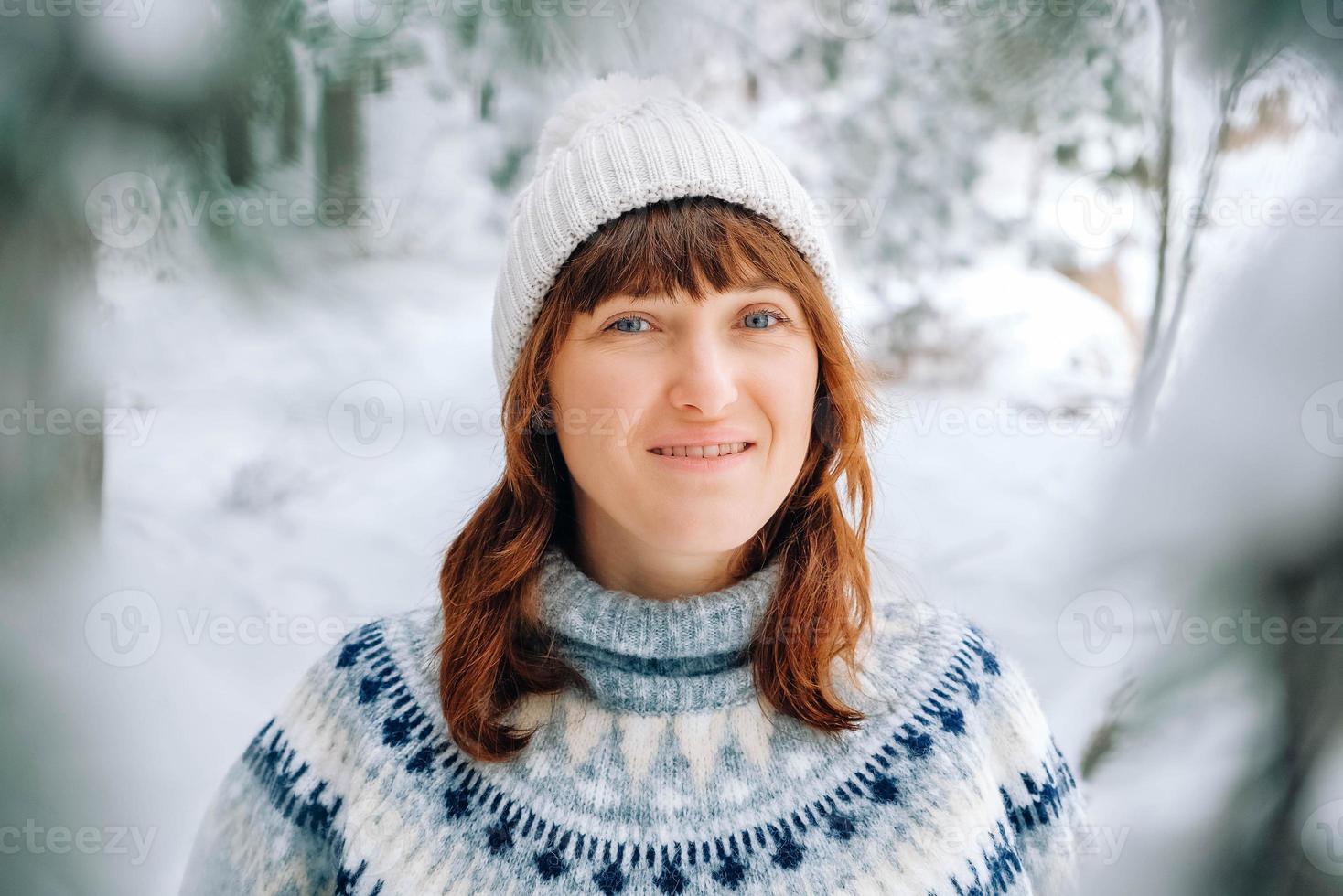 retrato de inverno de uma mulher com um chapéu quente e suéter em um fundo de floresta nevada foto