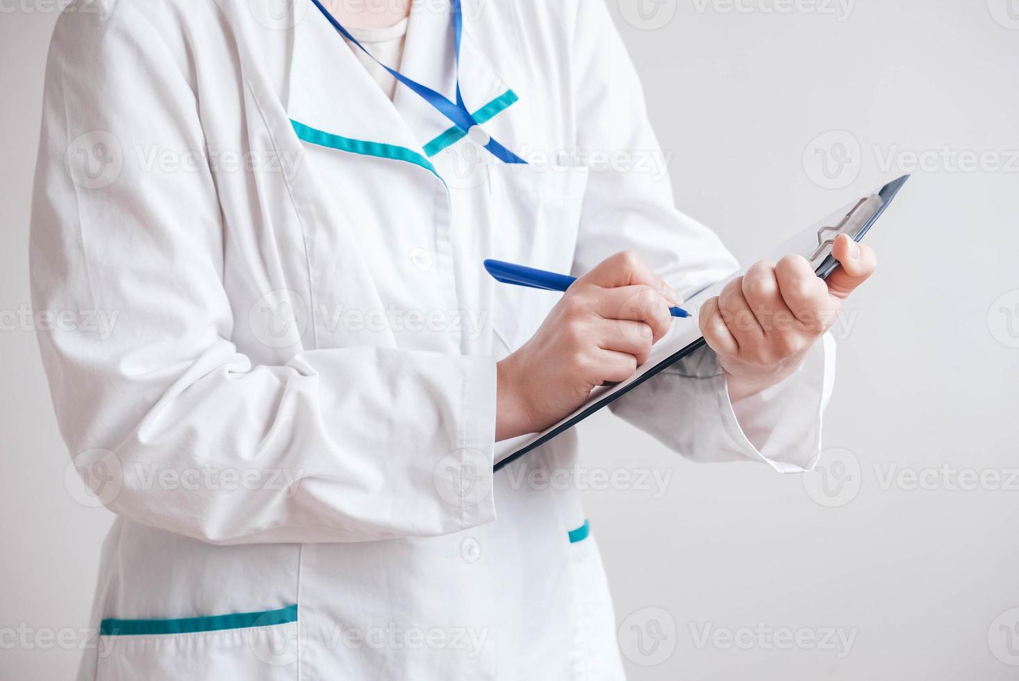 médica de jaleco branco faz uma entrada na pasta em um fundo branco. copiar, espaço vazio para texto foto
