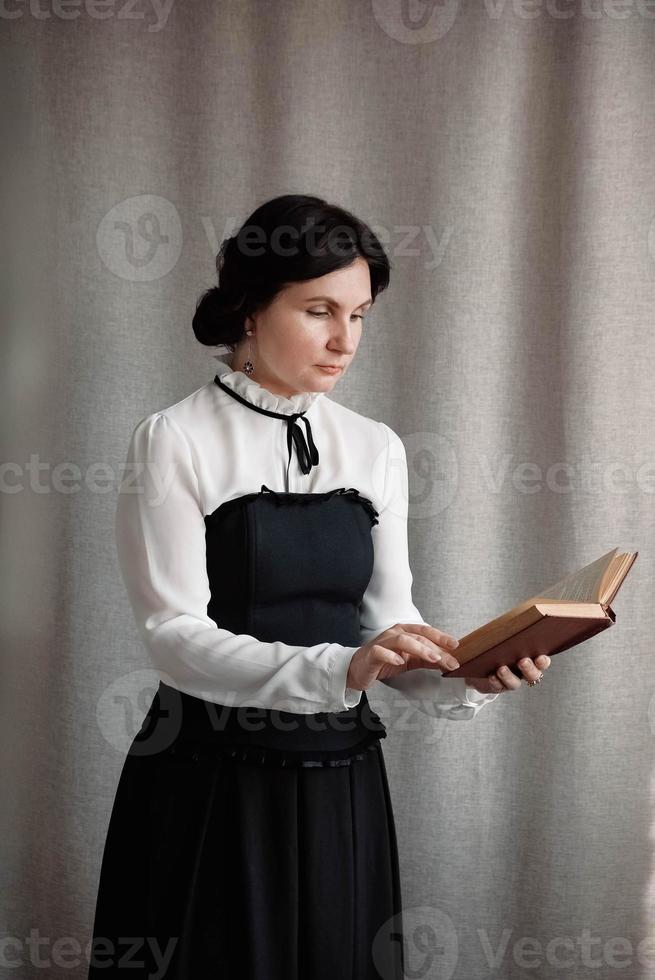 retrato de uma mulher em estilo vintage vestida segurando um livro nas mãos em um fundo de pano de linho foto