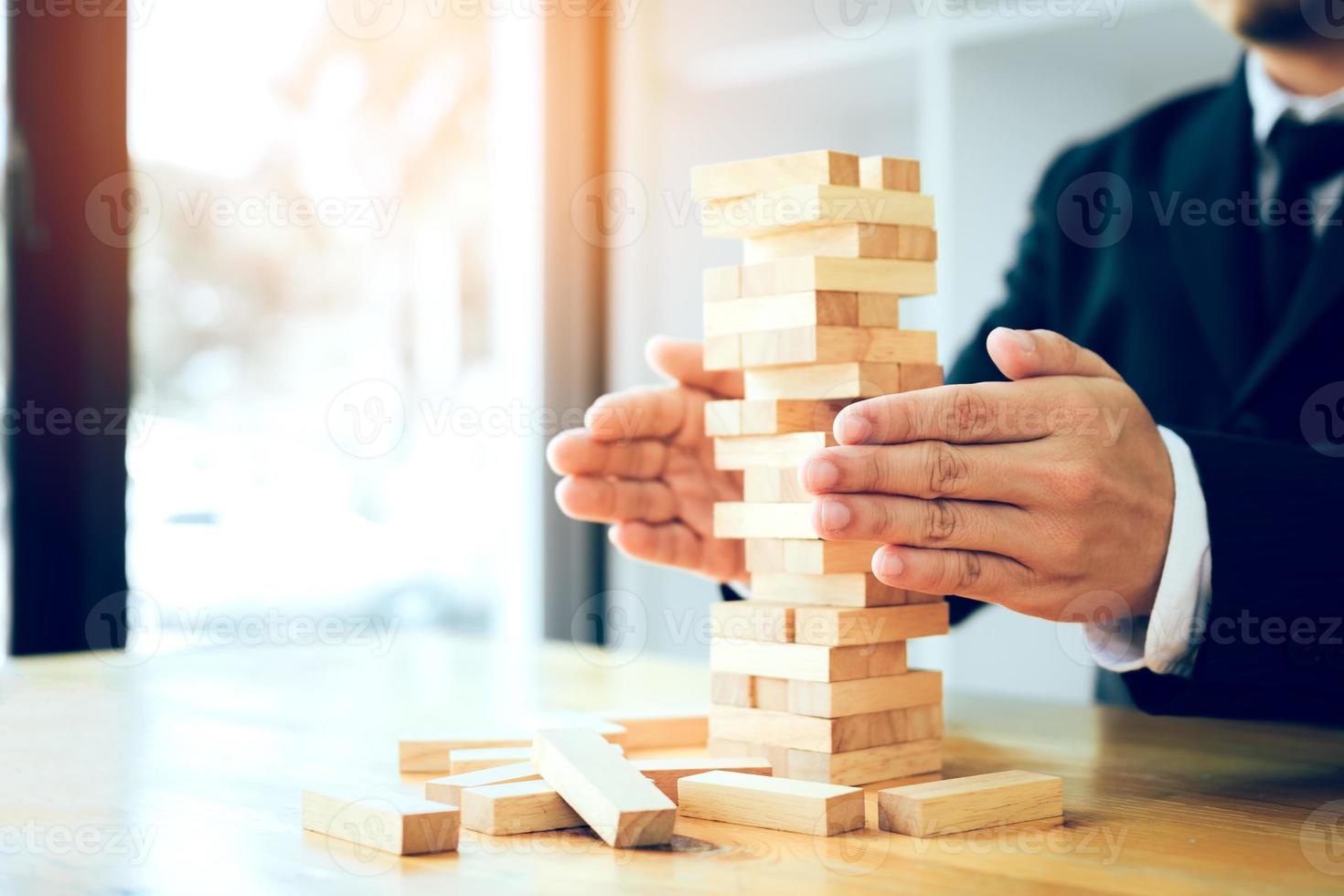 as mãos do empresário protegem o bloco de madeira na mesa com o conceito de risco. foto