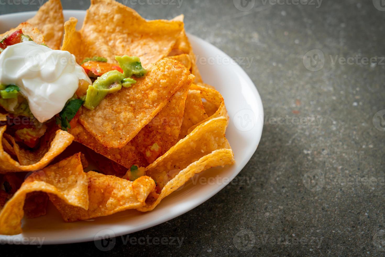 chips de tortilha de nachos com jalapeño, guacamole, molho de tomate e molho foto