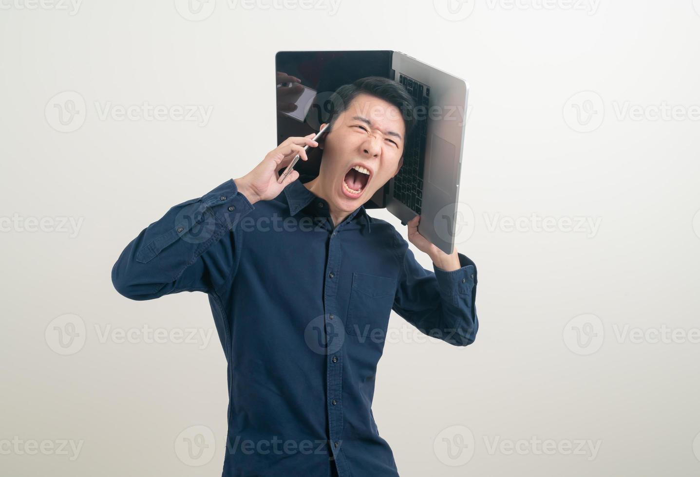homem asiático falando em smartphone ou celular e segurando uma mão no laptop foto