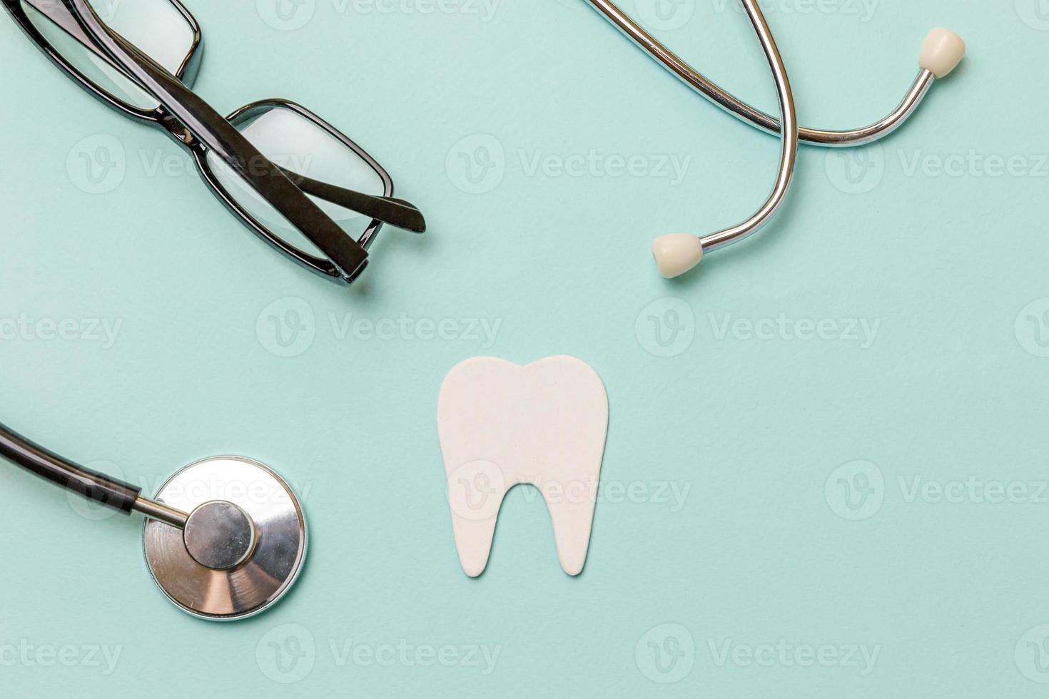 conceito de atendimento odontológico de saúde. óculos de dente saudável branco estetoscópio de equipamentos de medicina isolados em fundo azul pastel. dispositivo de instrumento para médico dentista. higiene bucal dental, dia do dentista. foto