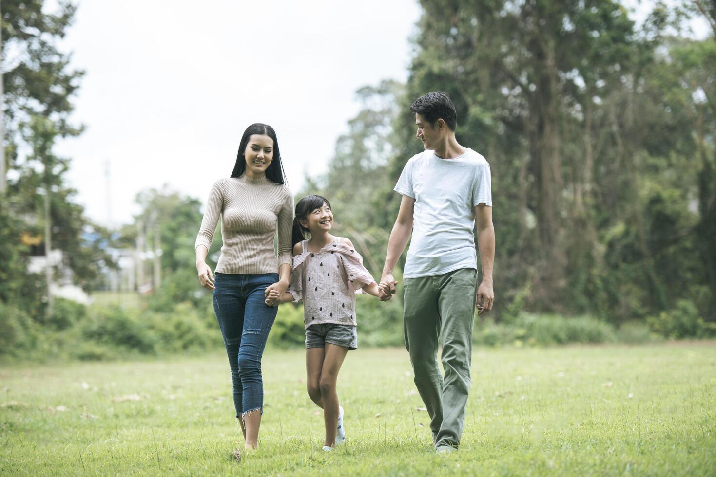 pais felizes e sua filha andando no parque, conceito de família feliz. foto