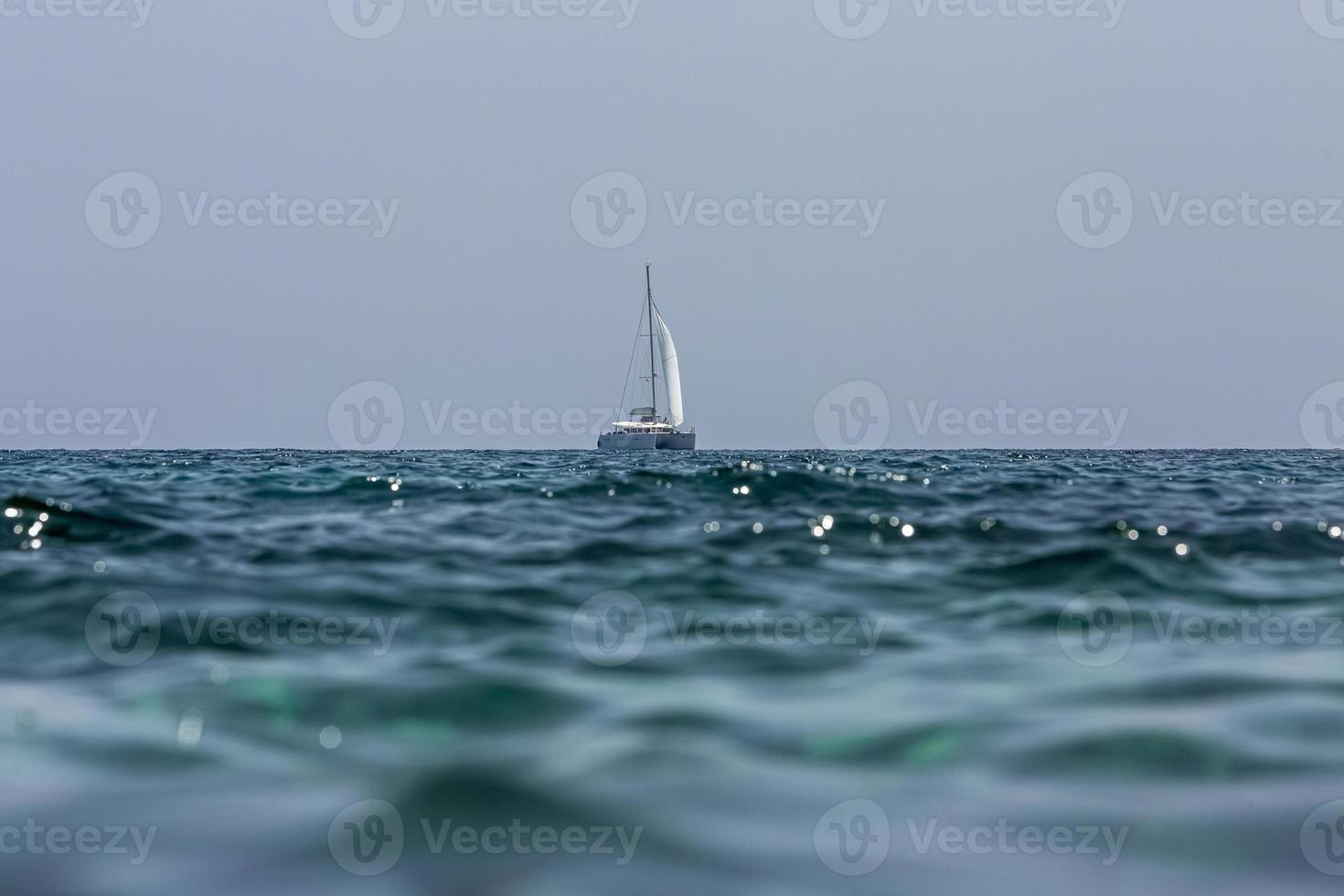 catamarã barco à vela branco no oceano perto da praia. foto