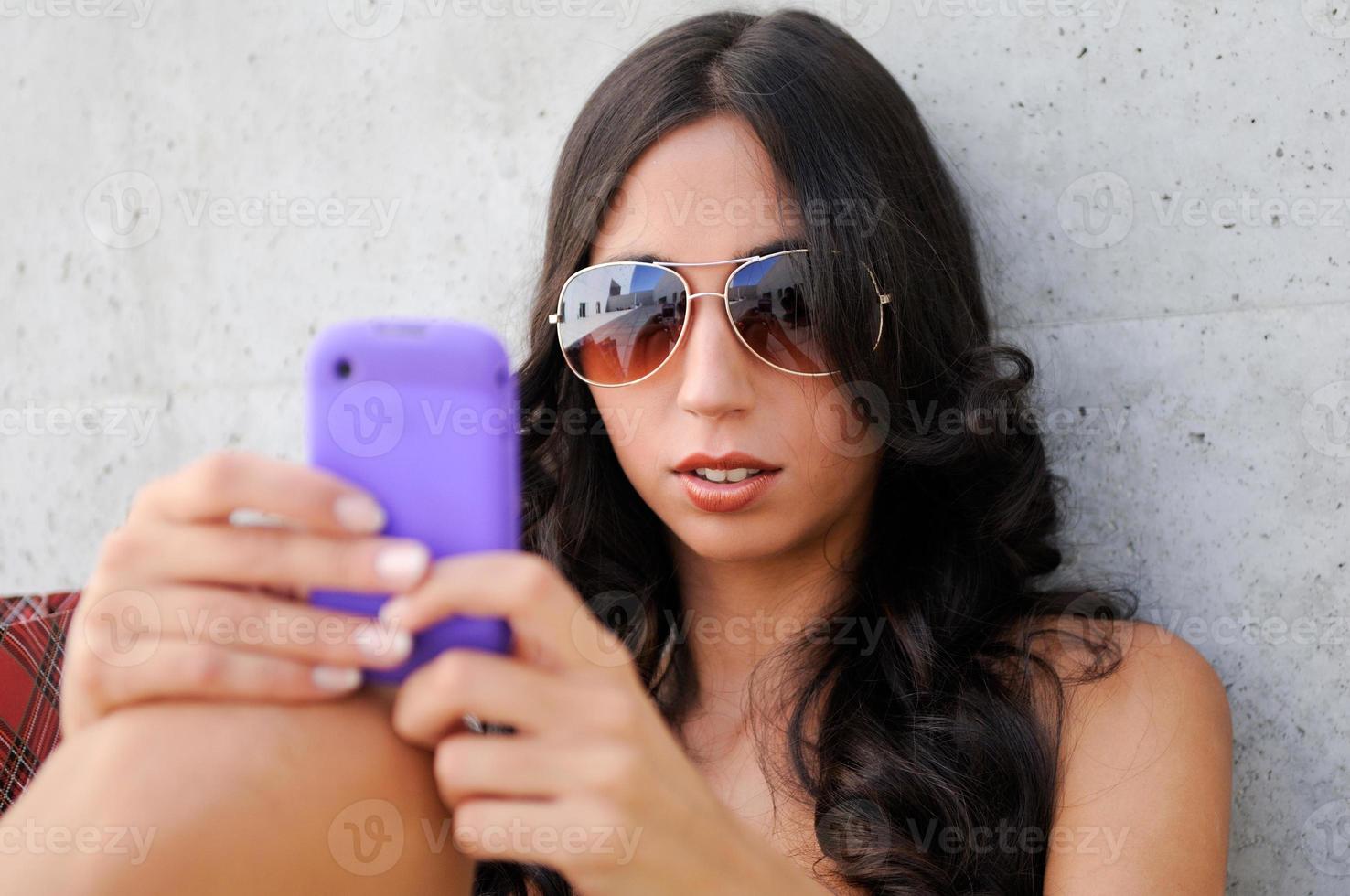 mulher jovem e bonita com um smartphone em um prédio de escritórios foto