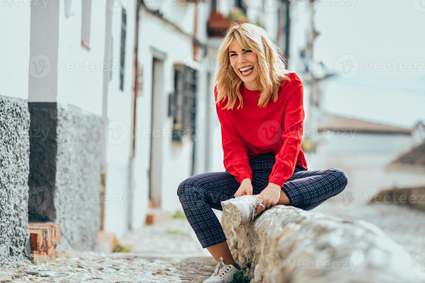 loira sorridente com camisa vermelha, curtindo a vida ao ar livre. foto