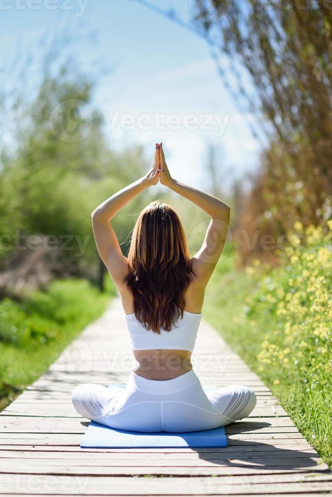 jovem e bela mulher fazendo ioga na natureza foto