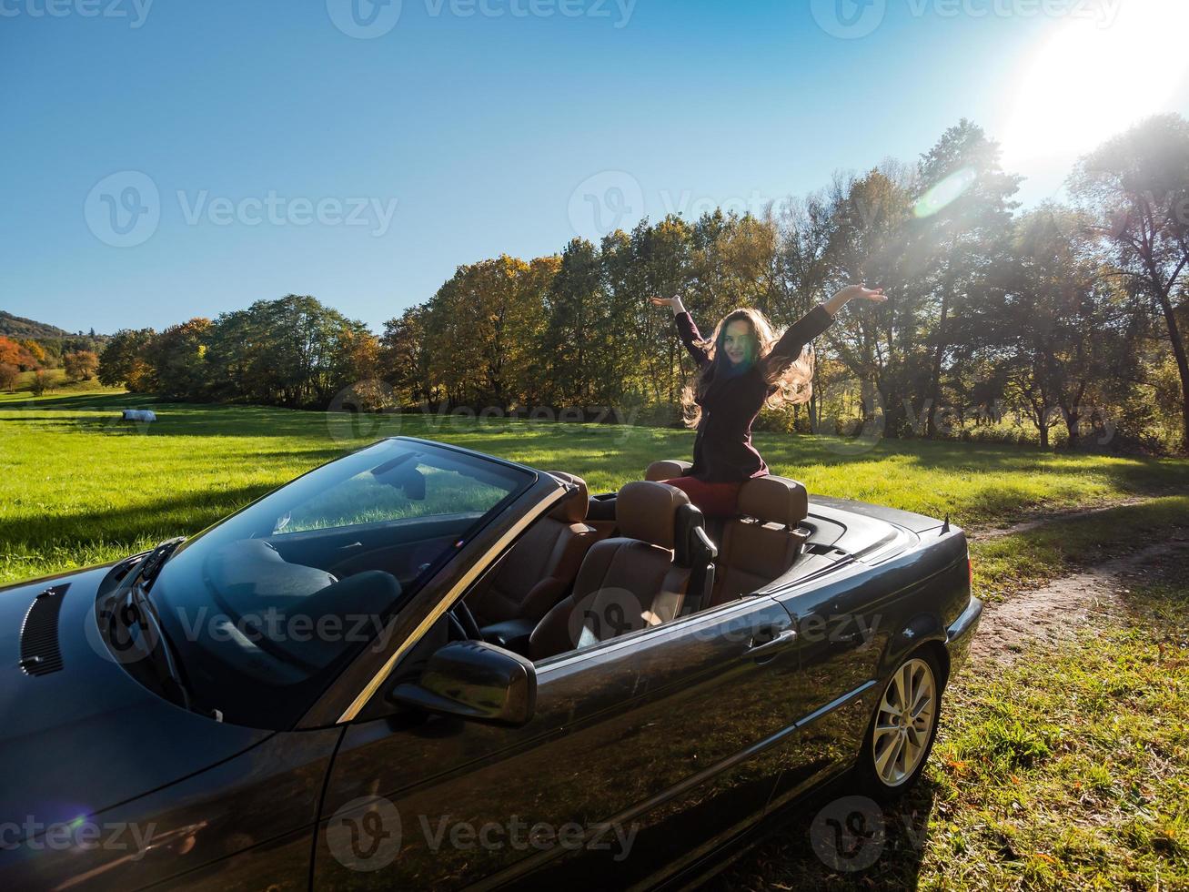 uma linda garota posando em um conversível, um carro retrô e uma beleza no sol brilhante do outono. foto