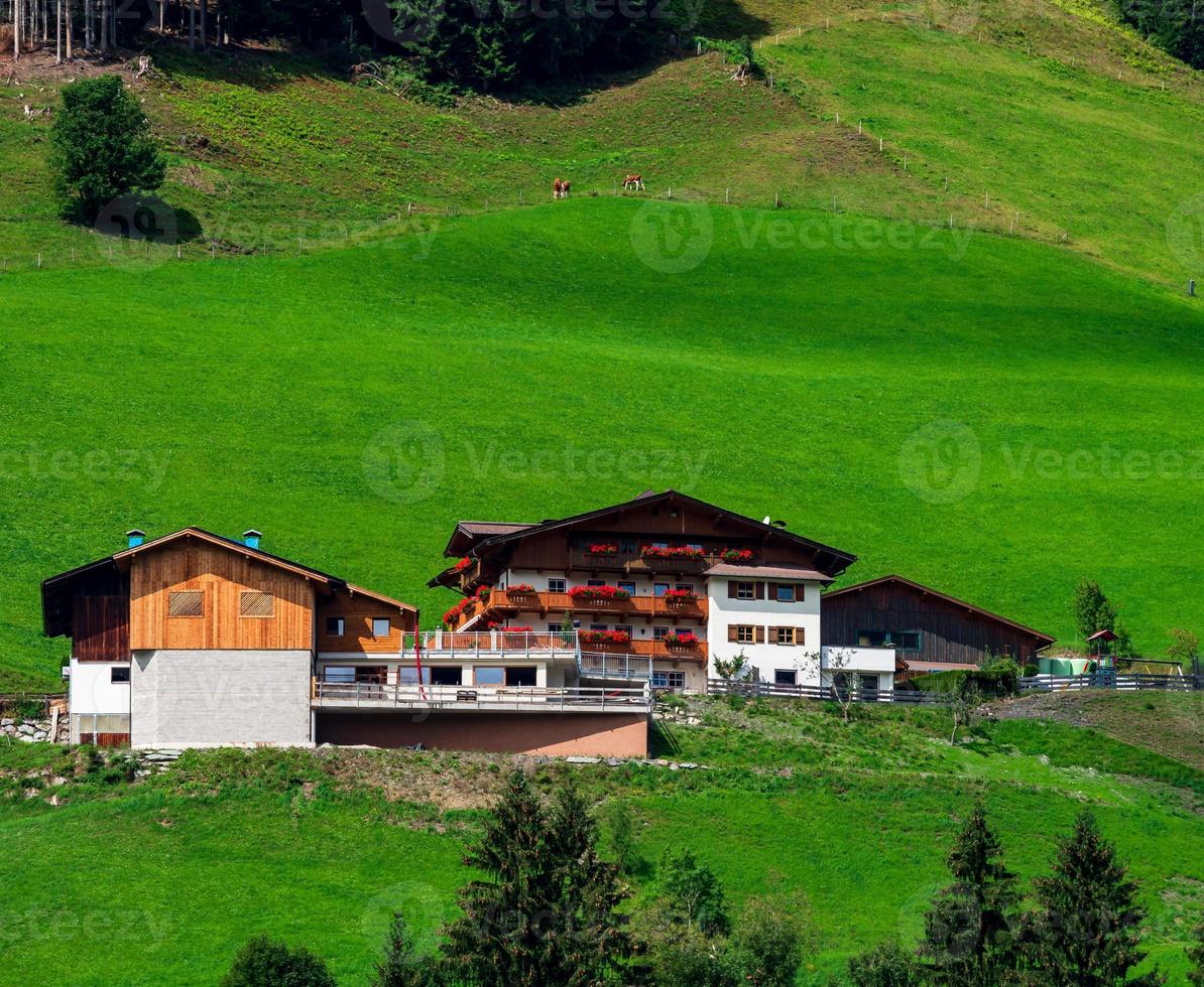 colinas verdes de um resort alpino na áustria no verão. pequena vila, hotéis e chalés, todos em cores. belos terraços e painéis solares nos telhados. a proximidade da civilização e da natureza pura. foto