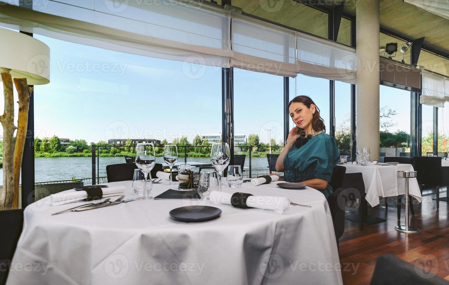 mulher jovem e bonita no interior de um restaurante com um copo de vinho foto