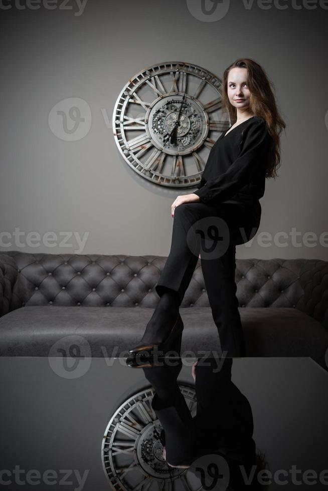 menina e tempo. linda jovem posando no contexto de um relógio de parede foto