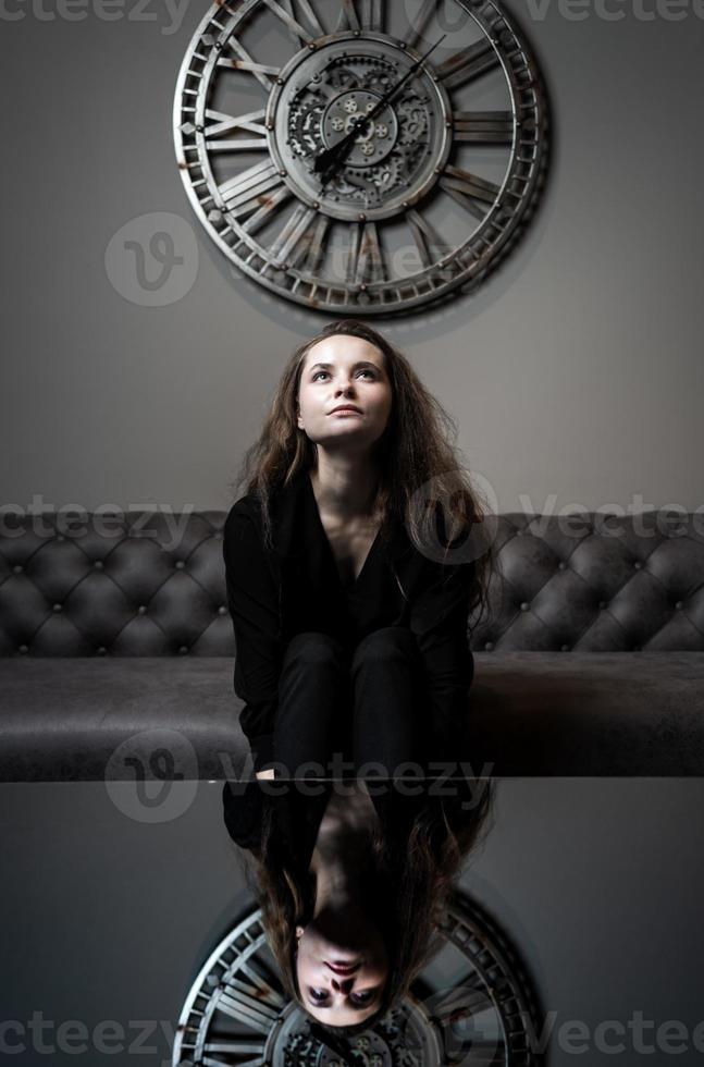 menina e tempo. linda jovem posando no contexto de um relógio de parede foto