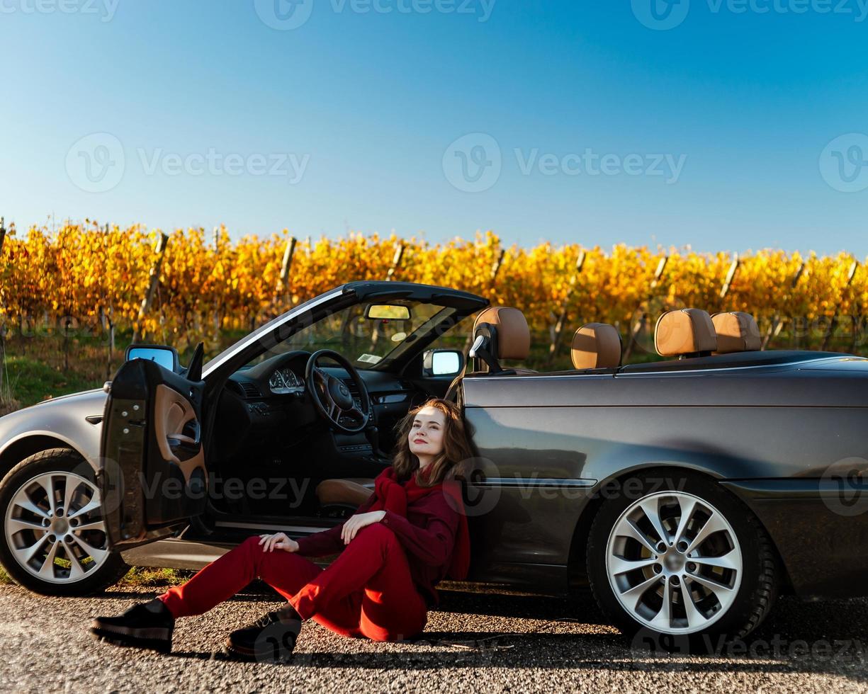 uma linda garota perto de um carro quebrado em um campo, um conversível retrô foto