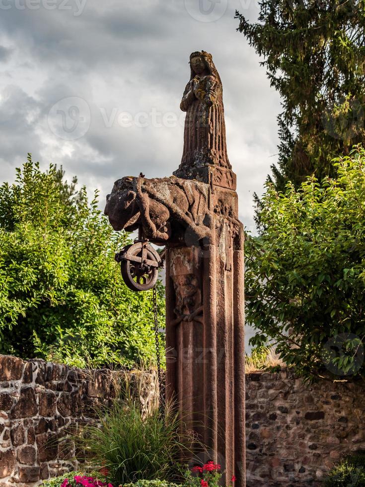 estátua de pedra medieval sobre um antigo poço, alsácia, território da abadia de andlau foto