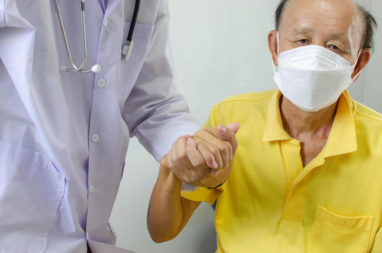 médico está segurando a mão de um homem idoso para animá-lo. foto