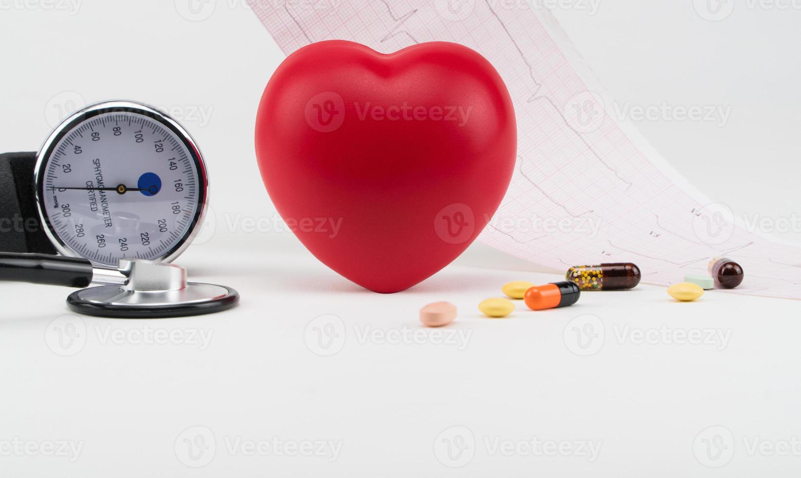 coração de brinquedo e tonômetro no fundo de um eletrocardiograma. conceito de saúde. cardiologia - cuidados com o coração foto