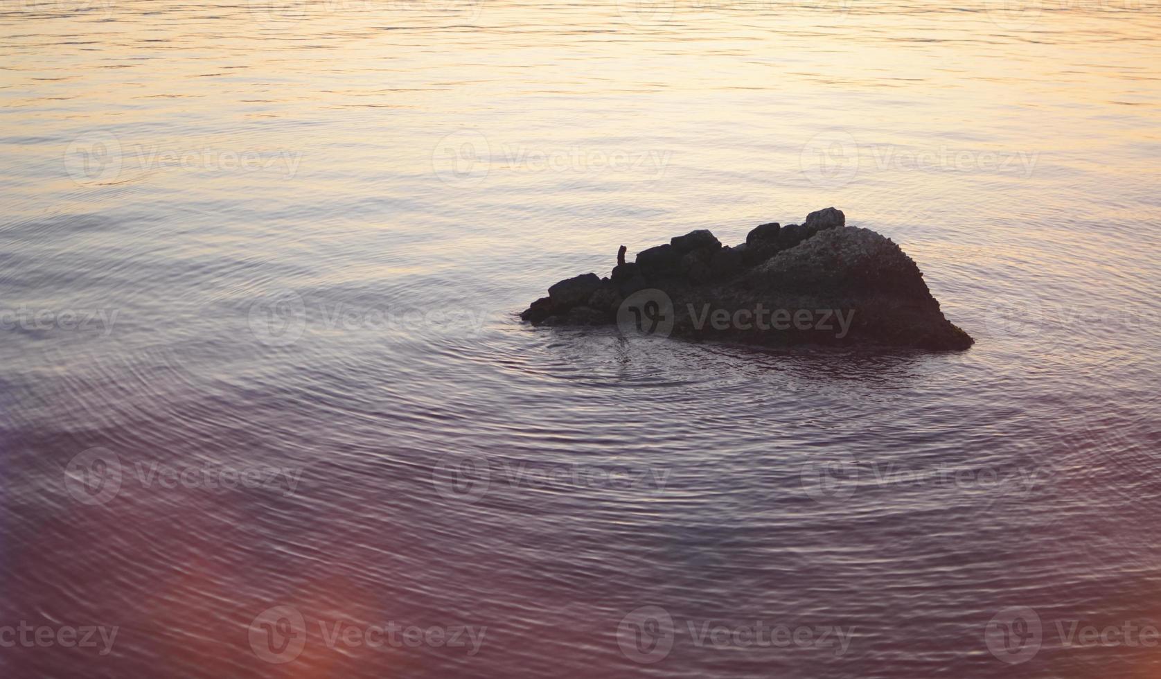 rocha que sobe isolada no mar foto