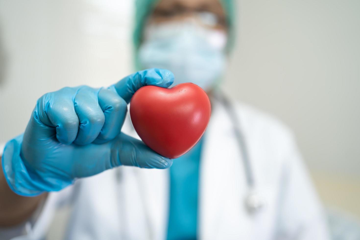 médico usando epi com máscara para proteger coronavírus segurando coração vermelho. foto