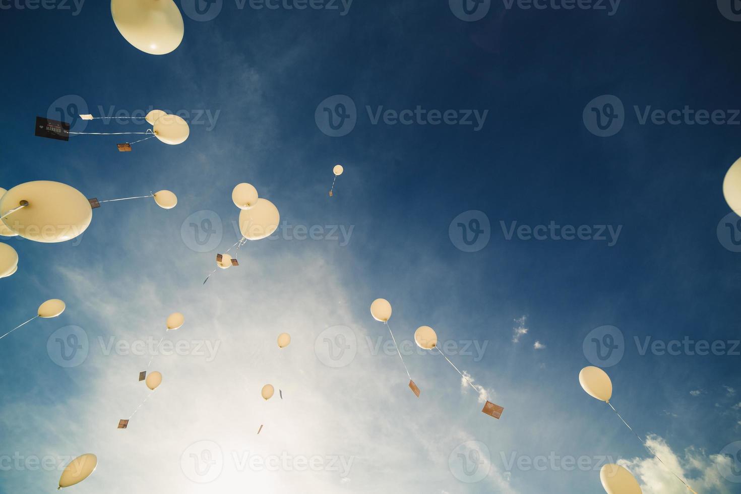 balões brancos voam para o céu azul. o lançamento de balões festivos nas nuvens. celebração e felicidade. bolas de gel de ar na atmosfera. foto