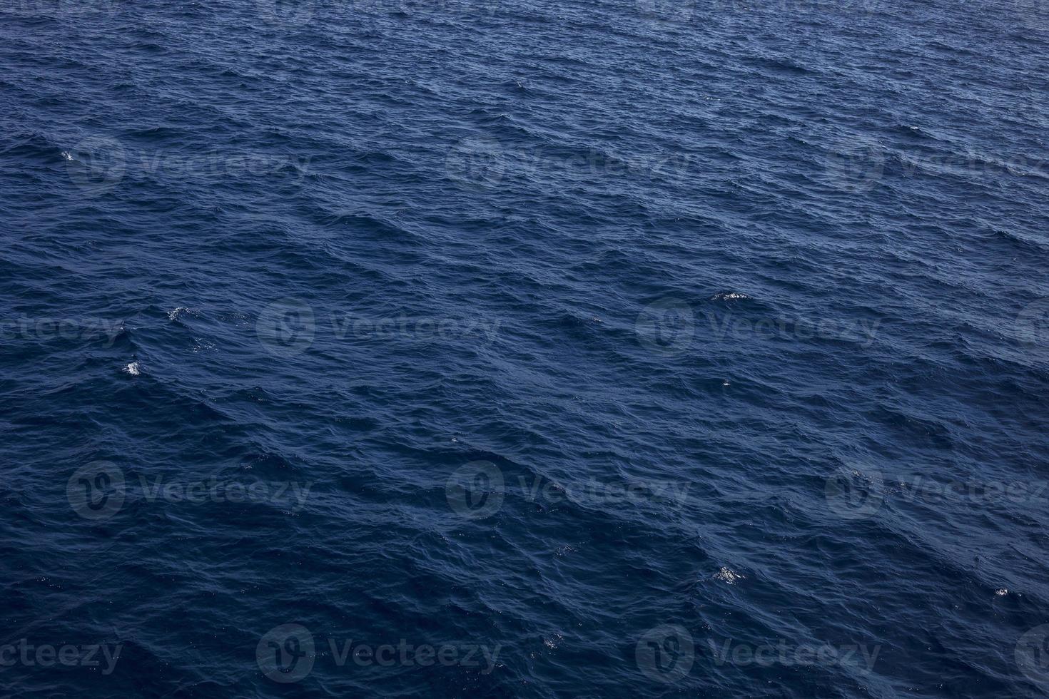 superfície de ondas de água de tons azuis como pano de fundo. textura da água do mar. fundamentos é a superfície do fluxo de água do fluxo de água para convergir. foto