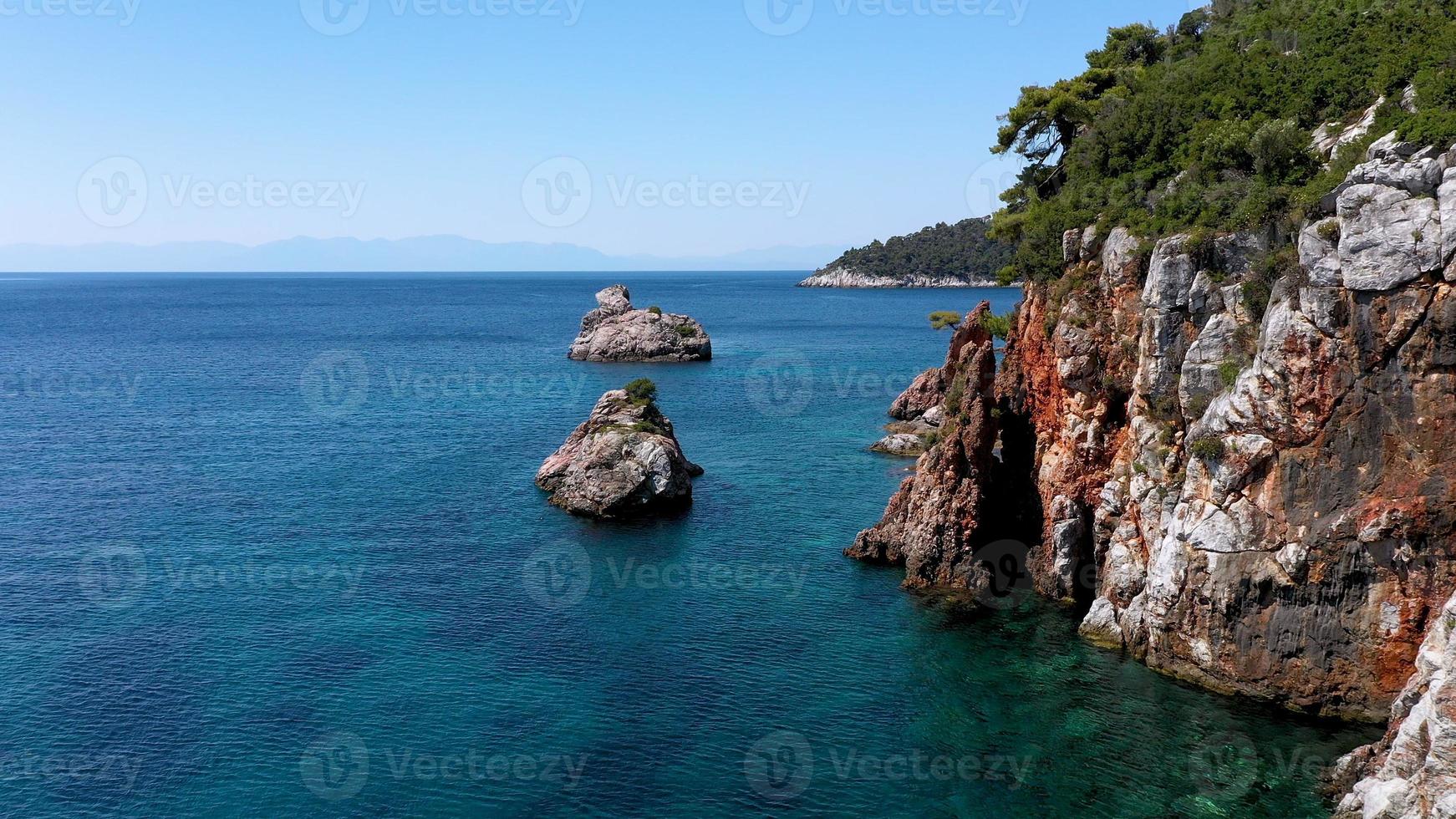 vistas aéreas de drones sobre um litoral rochoso, águas cristalinas do mar egeu, praias turísticas e muita vegetação na ilha de skopelos, grécia. uma visão típica de muitas ilhas gregas semelhantes. foto