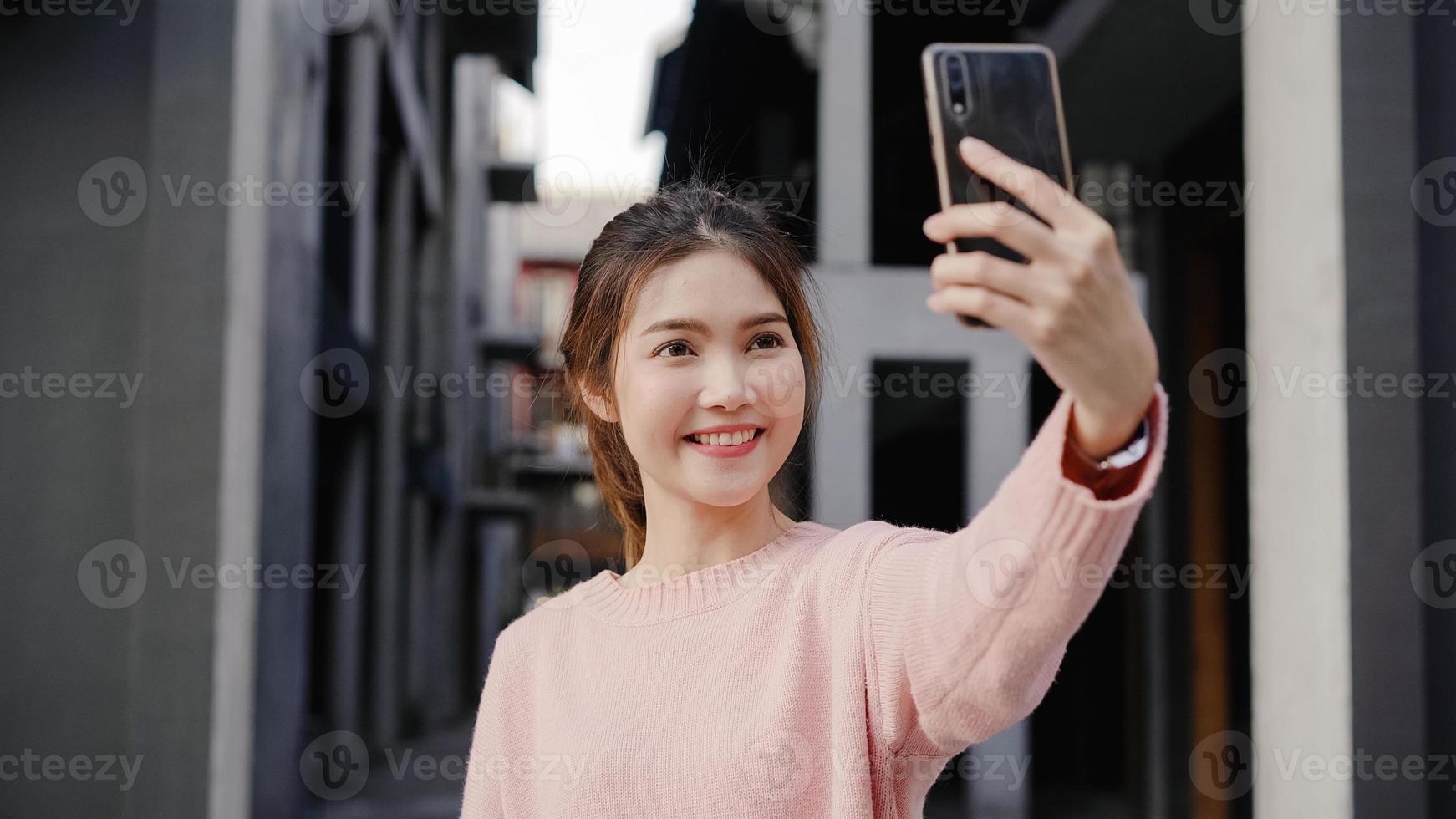 alegre linda jovem blogueira asiática usando smartphone tomando selfie enquanto viajava em chinatown em pequim, china. conceito de férias de viagem turística de mochila de estilo de vida. foto