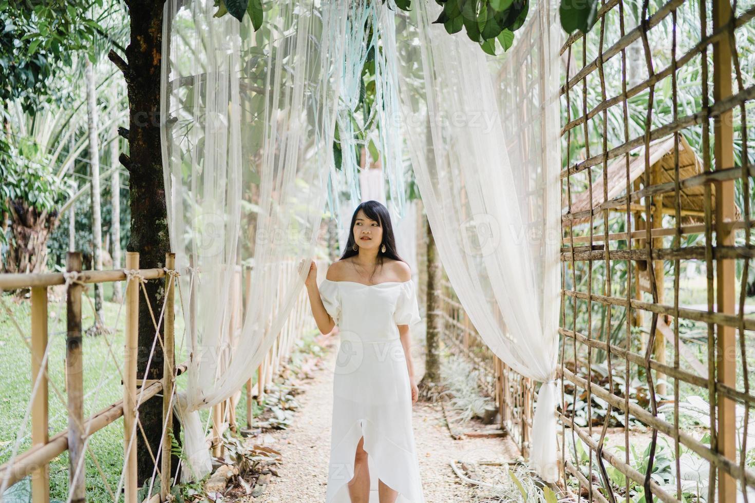 jovem mulher asiática relaxa na floresta, linda fêmea feliz usando o tempo de relaxamento na natureza. mulheres de estilo de vida viajam no conceito de floresta. foto