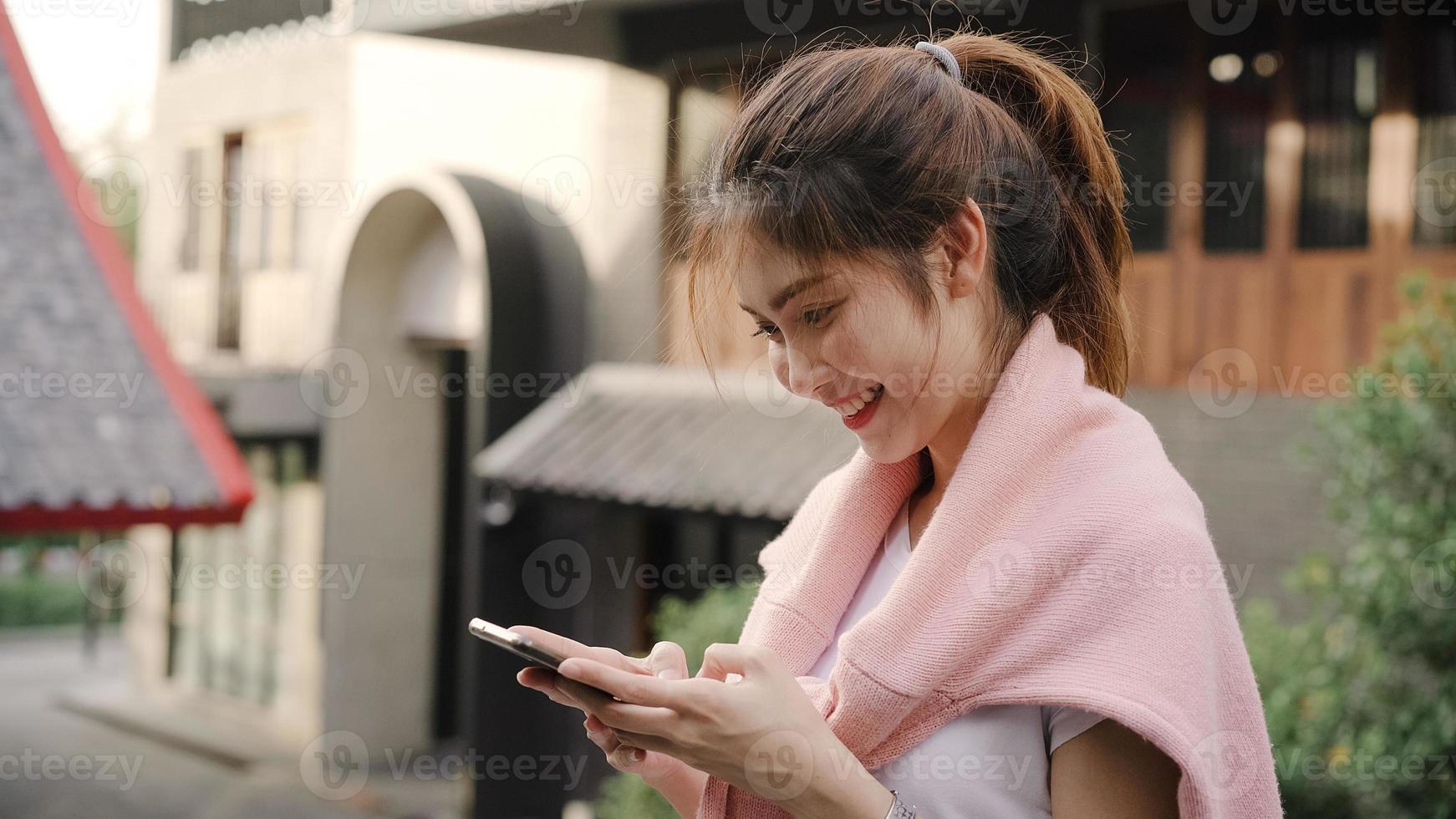 Mulher de blogueiro mochileiro asiático alegre usando smartphone para orientação e olhando no mapa de localização enquanto viaja em chinatown em Pequim, China. conceito de férias de viagens turísticas de mochila de estilo de vida. foto