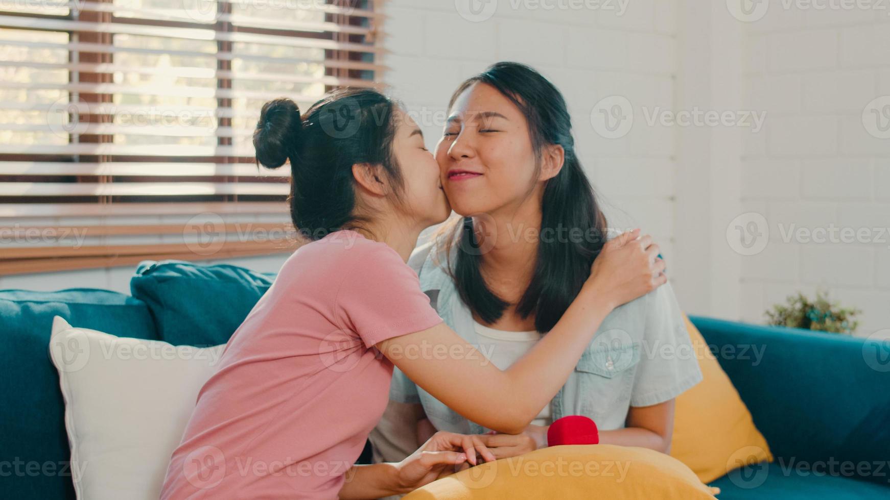 asian lésbicas lgbtq mulheres casal propor em casa, jovem amante da ásia feminino feliz sorrindo ter tempo romântico ao propor e casamento surpresa usar anel de casamento na sala de estar em casa conceito. foto