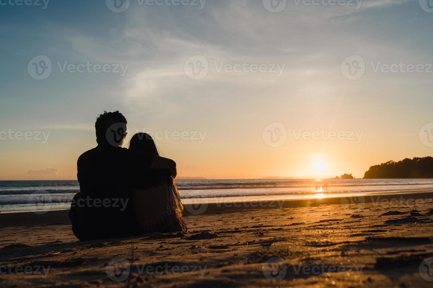 jovem casal asiático assistindo o pôr do sol perto da praia, doce casal feliz relaxa desfrutar de amor e momento romântico ao pôr do sol à noite. casal de estilo de vida viaja no conceito de praia. foto